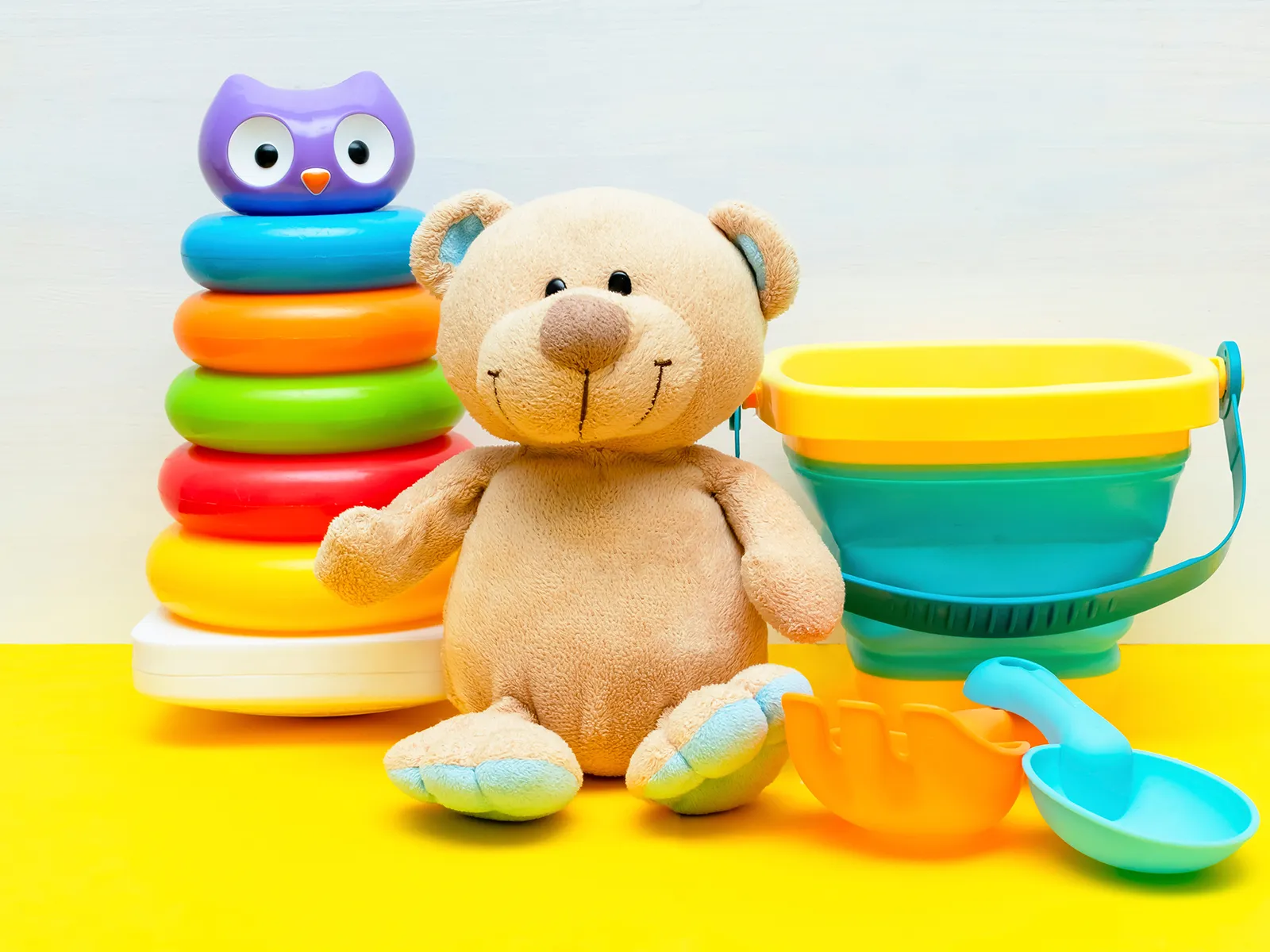 Oyuncak ayı, renkli halka kulesi ve plastik kum oyuncakları